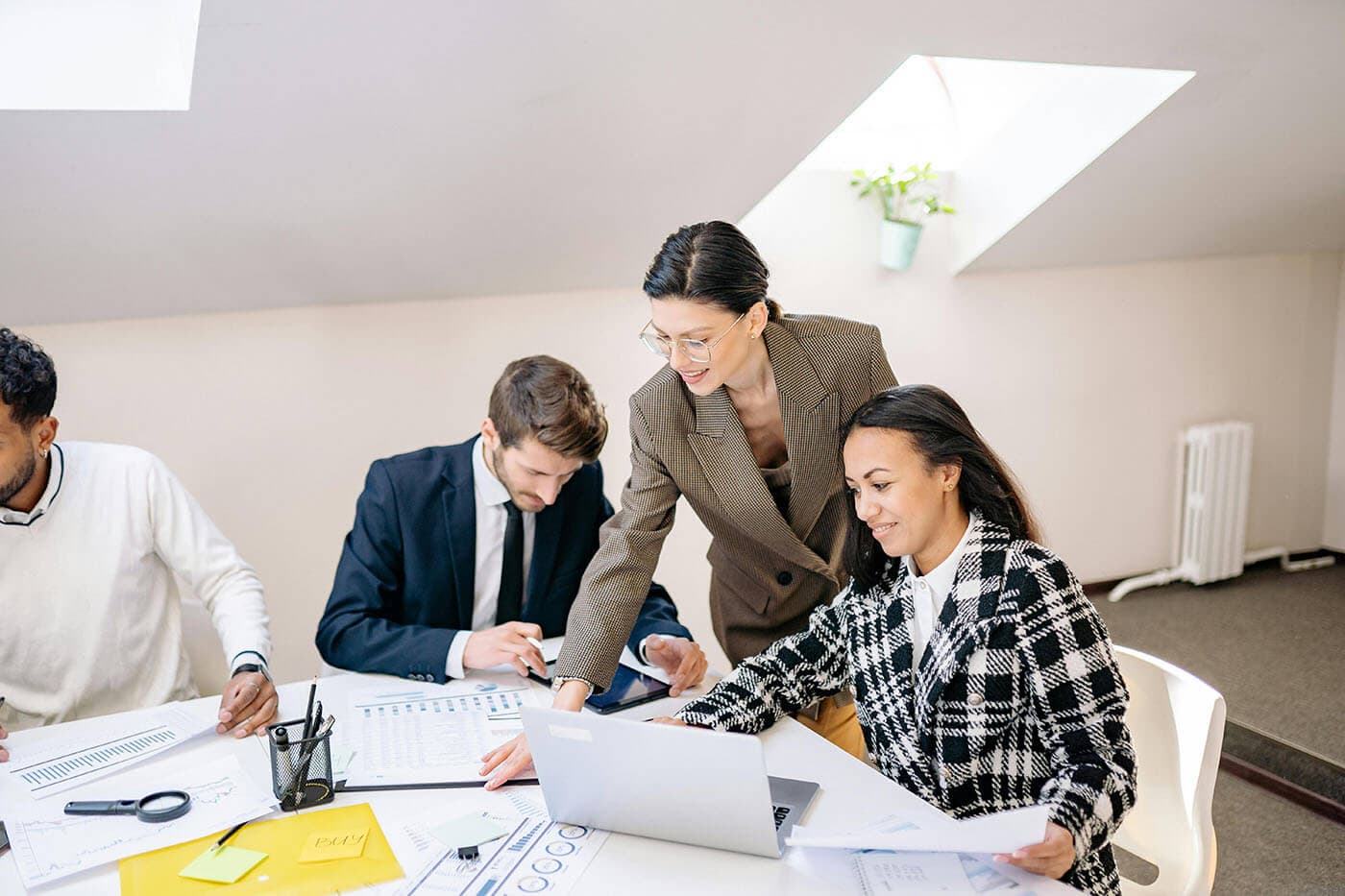 A manager leans in to help a team working at a table