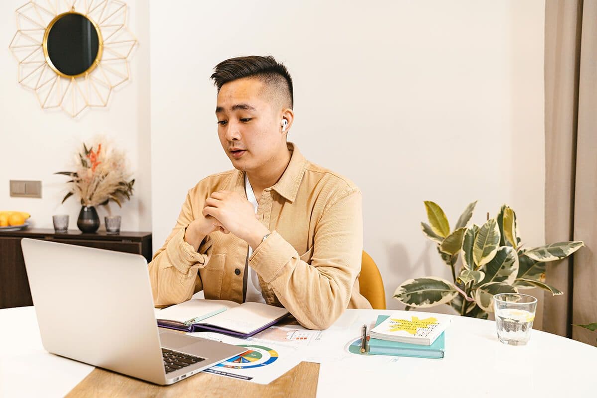 A remote manager sitting at a table in his home engaging in a one-on-one with his remote direct report