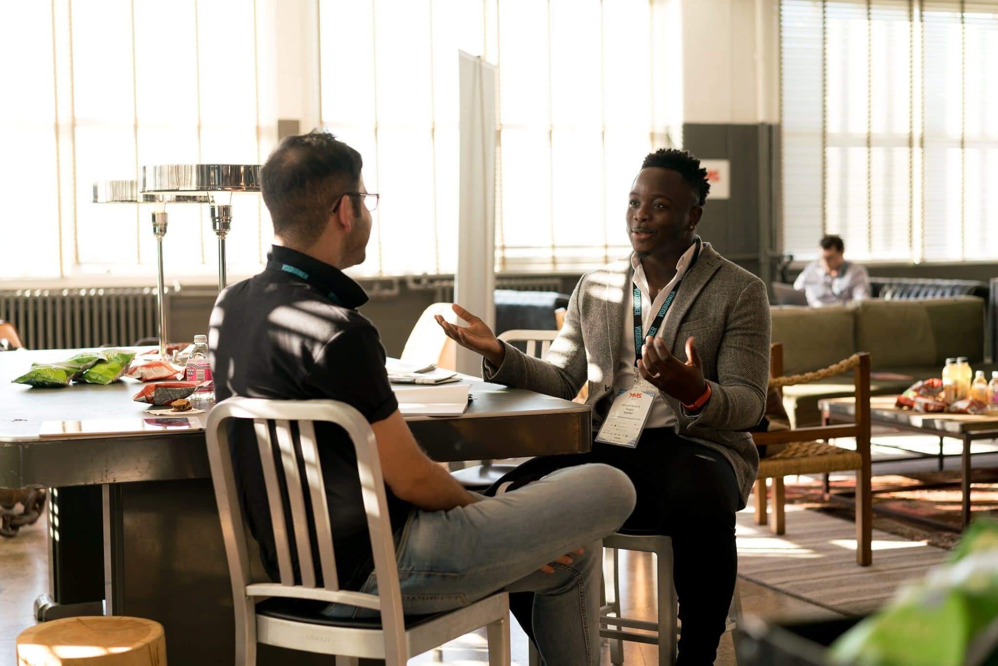 two men sit at table discussing mentoring challenges