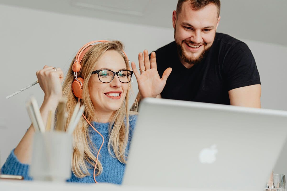 Two colleagues sitting in an office at a laptop having a meeting with their remote employee