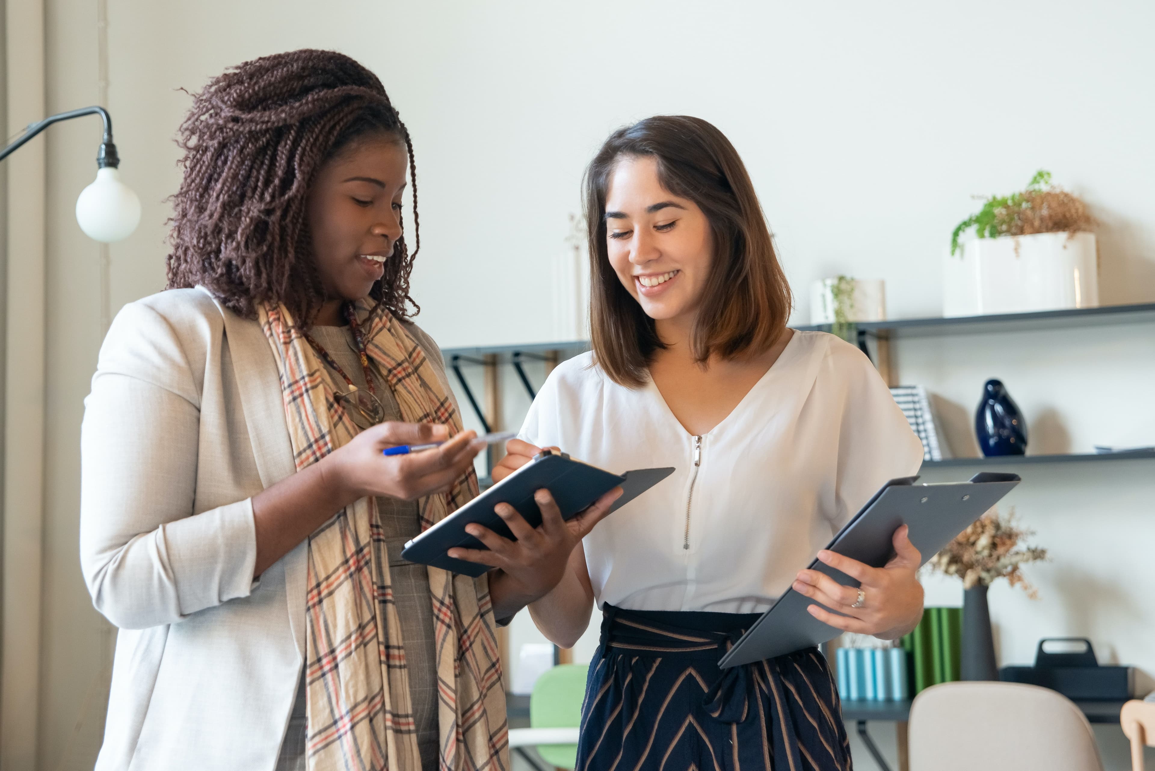 two diverse women employees working on project in the workplace