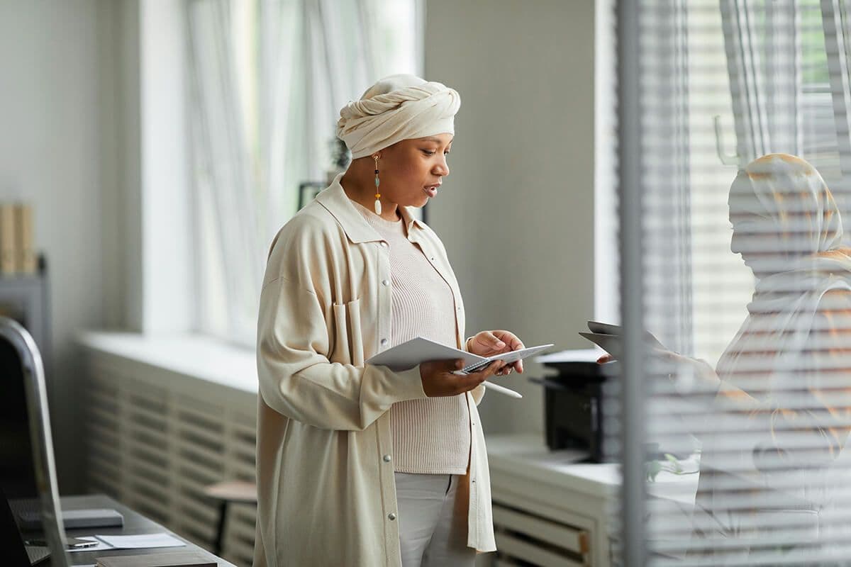 Two women employees with head scarves talking in a conference room about how the organization can be a more inclusive workplace culture.